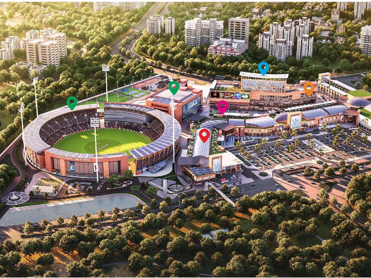 Aerial render of The Omaxe State, Dwarka: the Omaxe International Stadium on the left, the retail, food, club and hotel buildings with surface parking on the right, surrounded by trees and residential towers