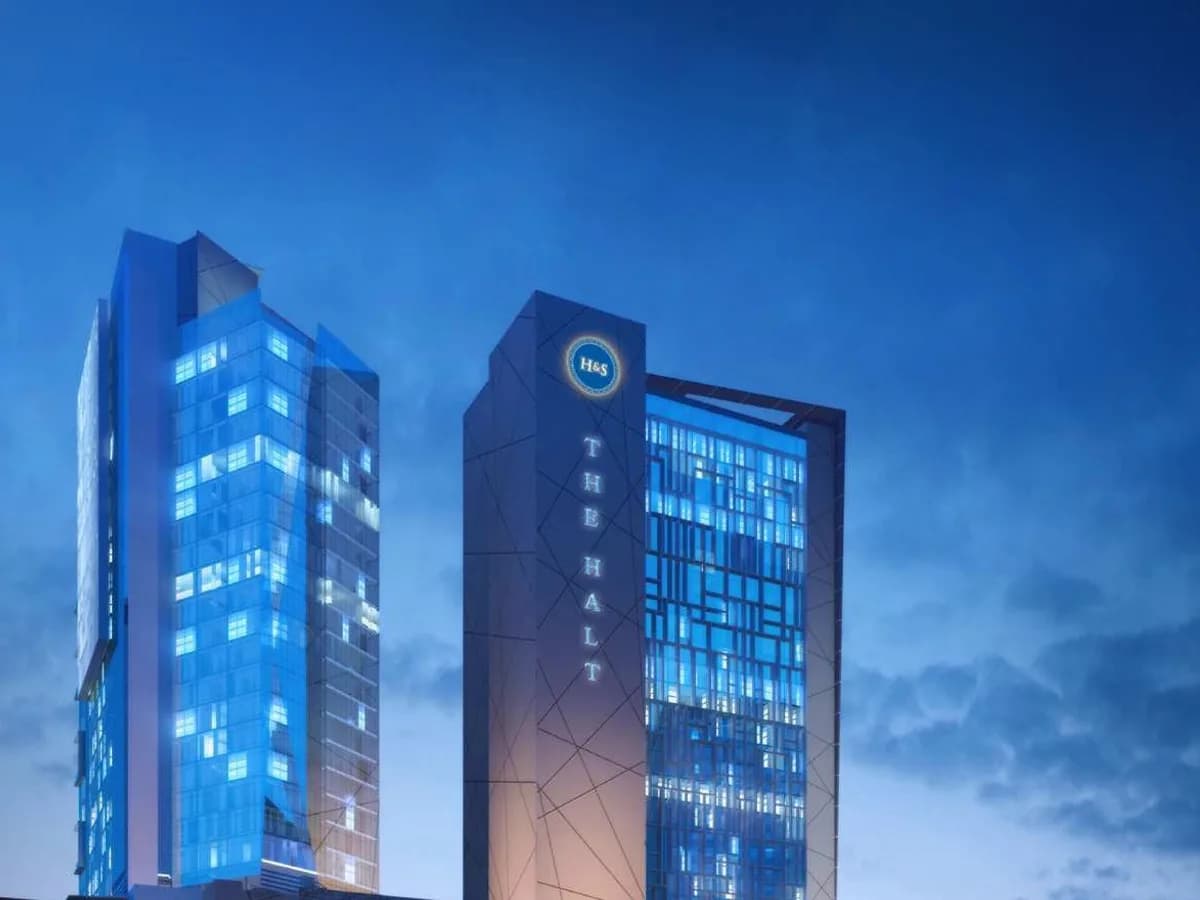 Night render of Boulevard Walk in Greater Noida West: the lit glass Wing office tower beside The Halt tower, above the mall podium