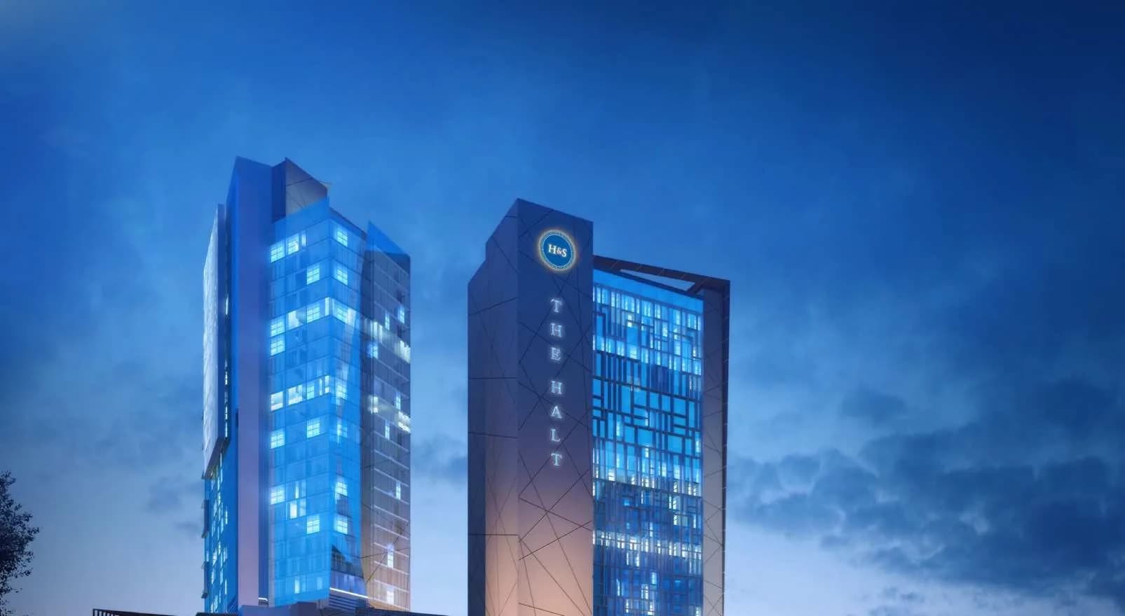 Night render of Boulevard Walk in Greater Noida West: the lit glass Wing office tower beside The Halt tower, above the mall podium