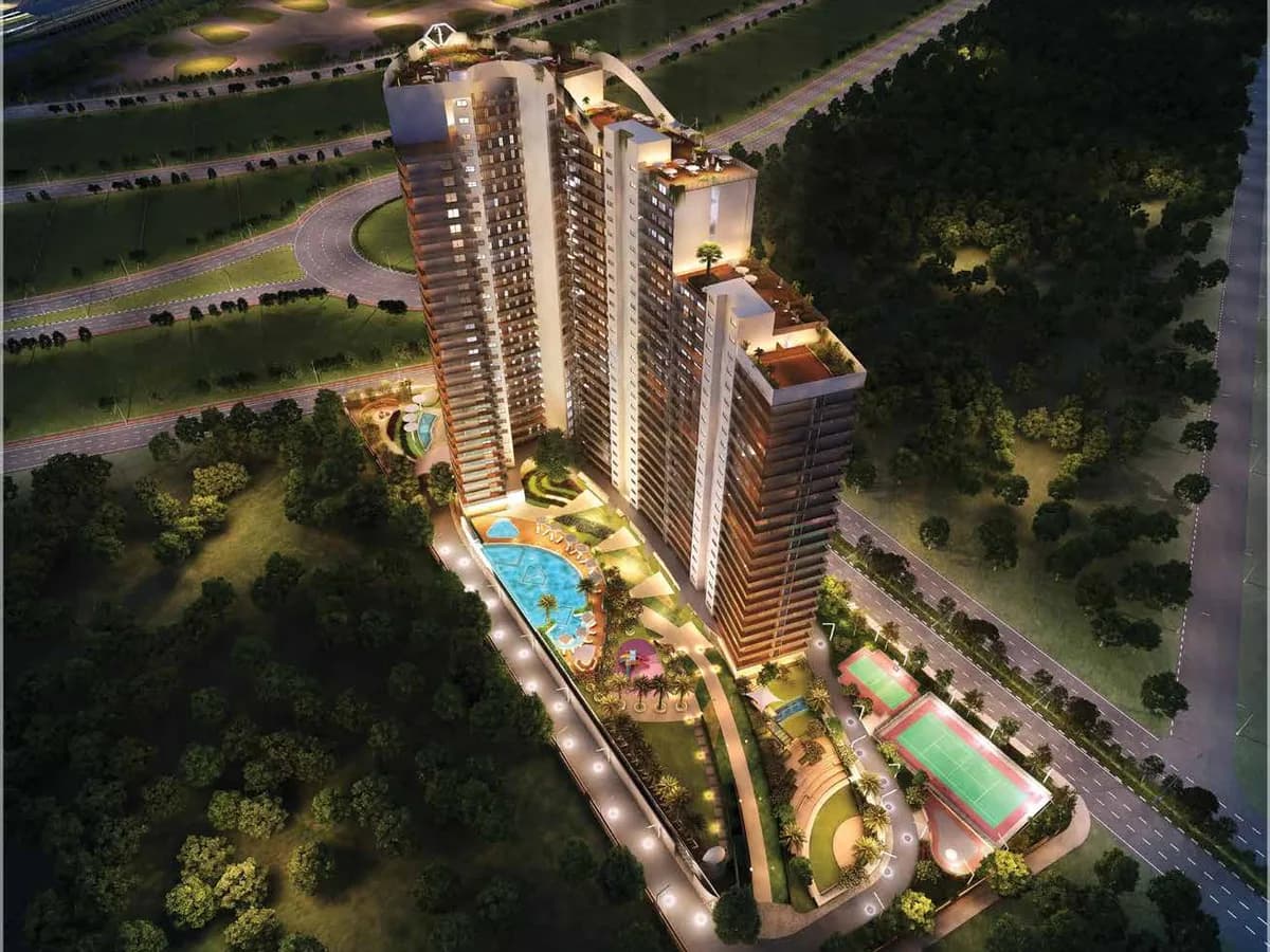 Artist's night aerial render of f Première by H&S: three linked towers above a lit podium with the main pool, amphitheatre and tennis court, beside the Yamuna Expressway