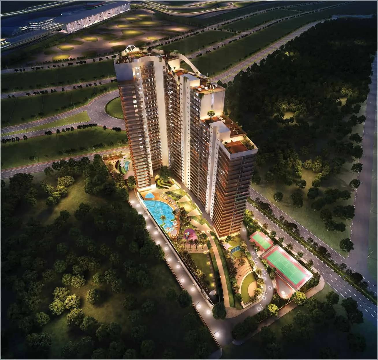 Artist's night aerial render of f Première by H&S: three linked towers above a lit podium with the main pool, amphitheatre and tennis court, beside the Yamuna Expressway