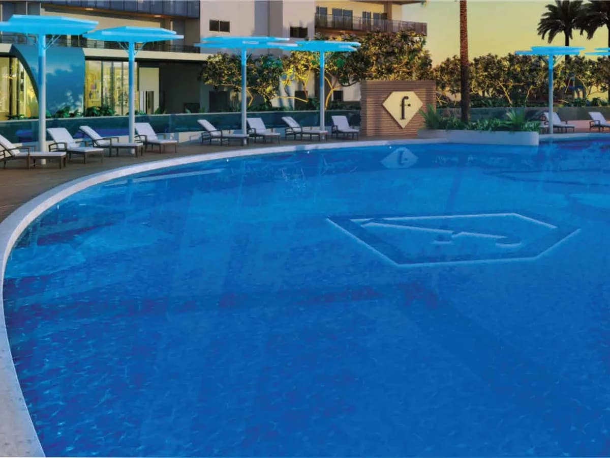 Artist's render of the Club Premiere pool at f Première, with loungers under blue canopies, planted screens and the 'f' diamond mark on the pool floor and poolside wall