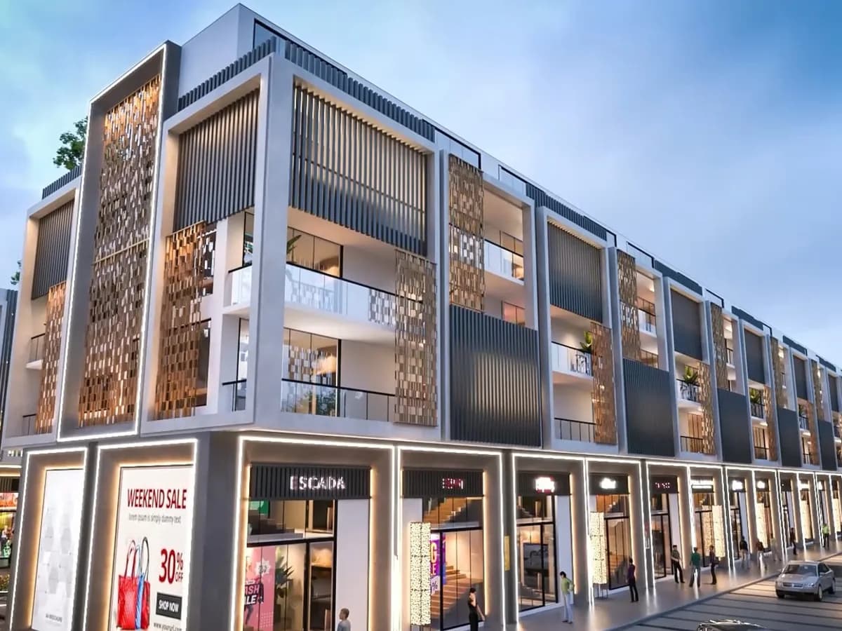 Render of the SCO row from the street, showing a long line of four-storey shop-cum-office units with lit retail frontages, balconies and kerbside parking along the internal road.