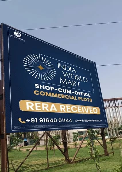 Site hoarding at Sector 88A announcing India World Mart shop-cum-office commercial plots and RERA registration received, with the project phone number and website.