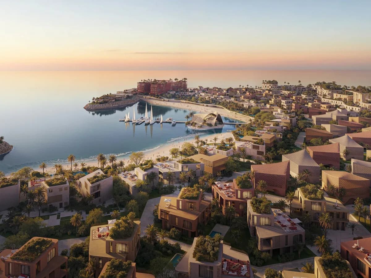 Aerial render of Mira Coral Bay at sunset: low-rise terracotta buildings stepping down to a beach, marina and yacht club