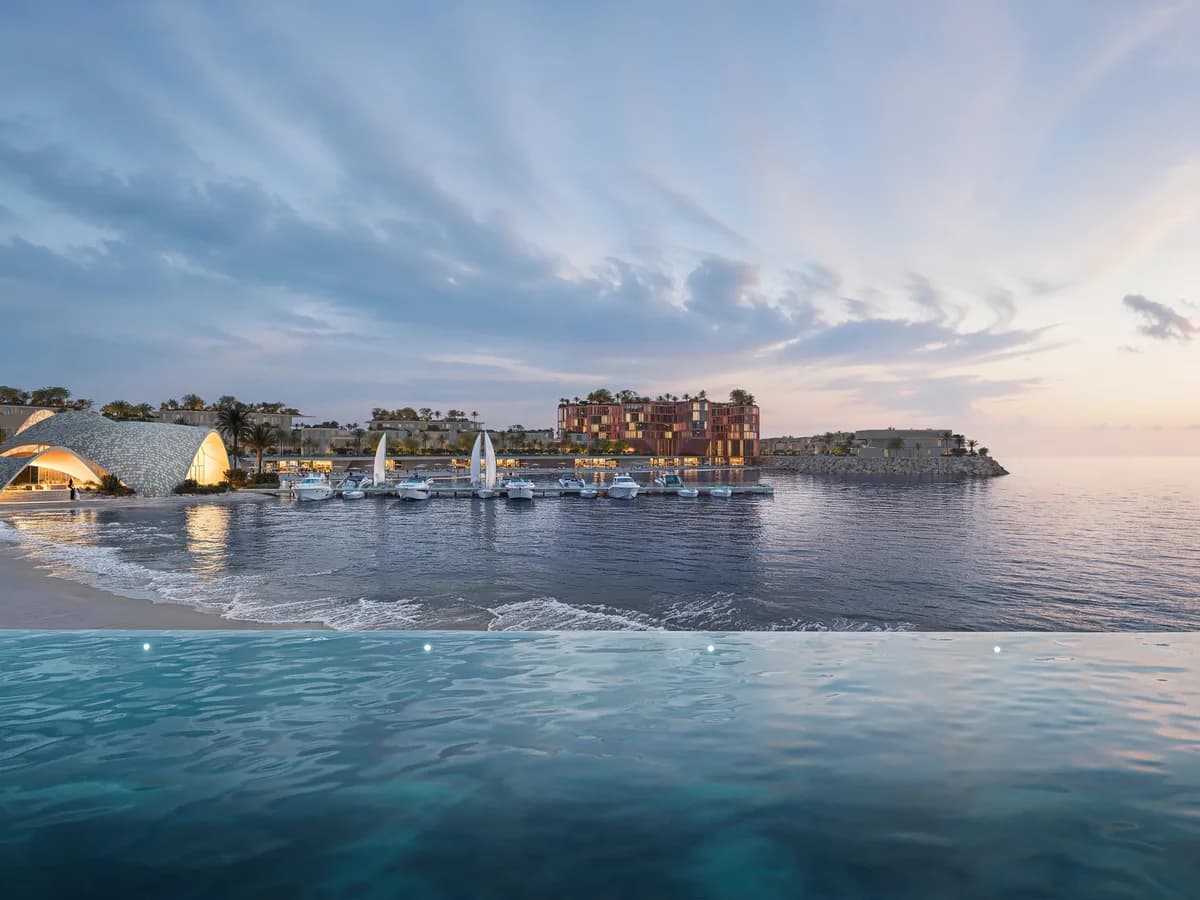 Render looking across calm water to the Mira Coral Bay beach, marina with sailboats and the yacht club at dusk