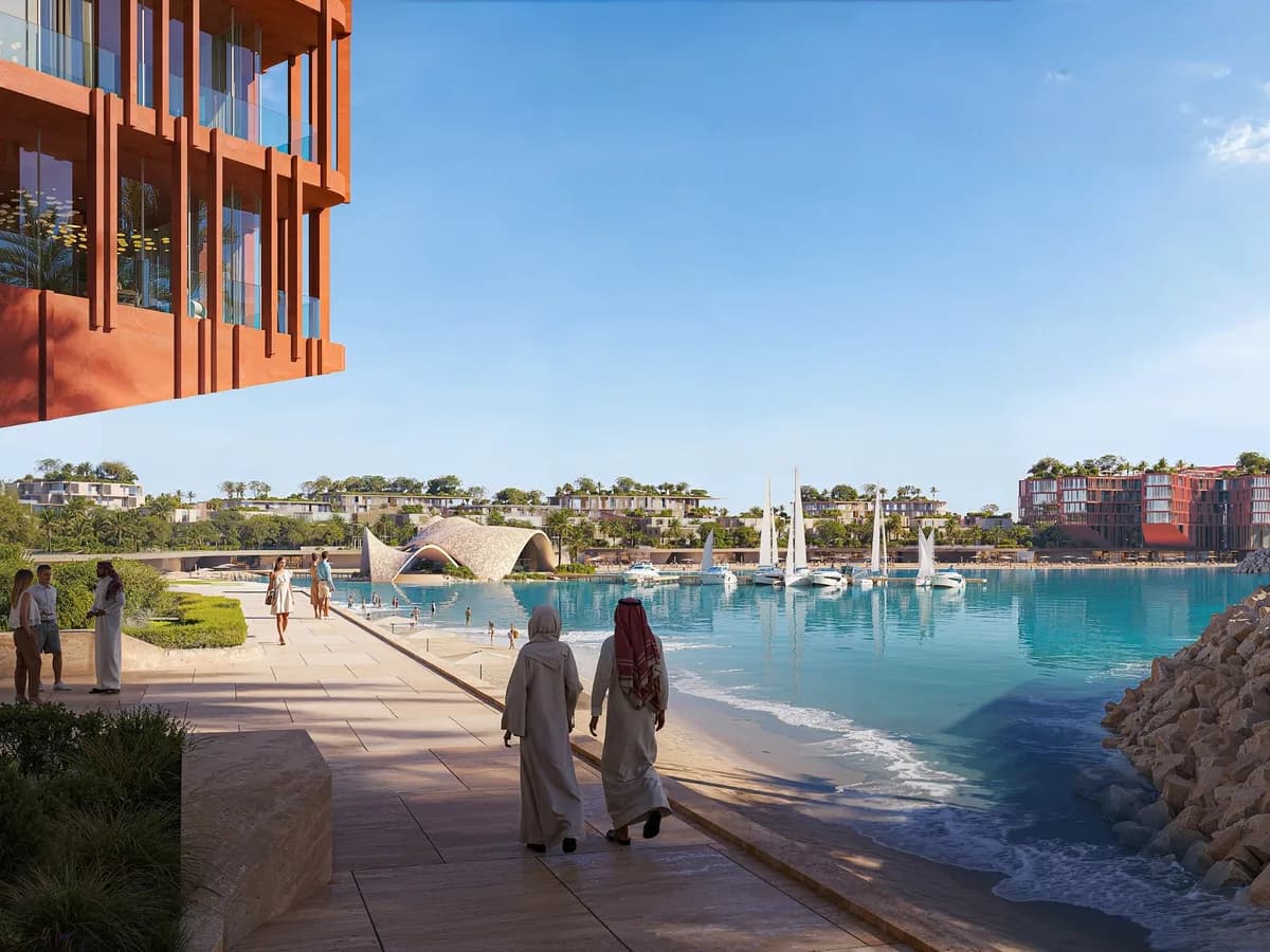 Render of a waterfront promenade with people walking beside a turquoise lagoon, rock revetment and marina in the distance