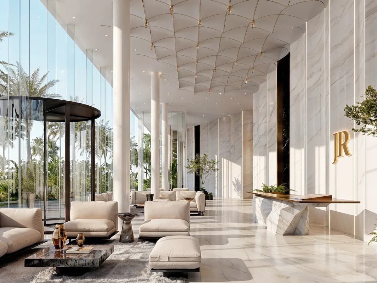 Render of a marble lobby with a revolving glass door, lounge seating, reception desk and a gold JR monogram on the wall